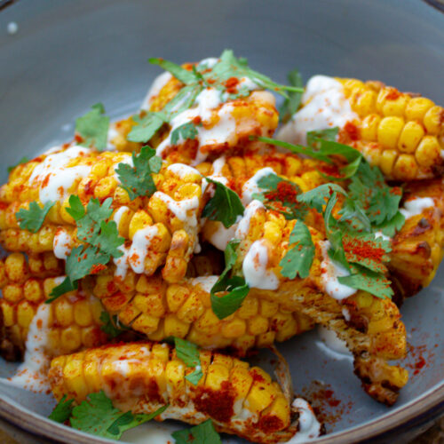 picture of corn in a blue bowl, drizzled with chilli mayo & sprinkled with parsley