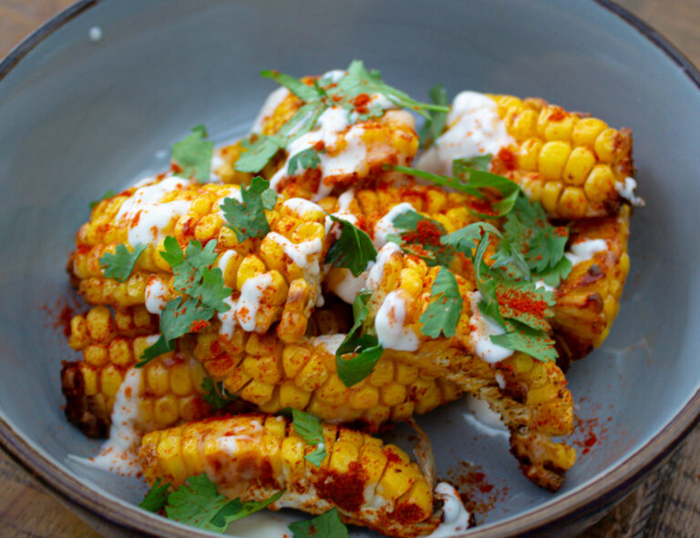 picture of corn in a blue bowl, drizzled with chilli mayo & sprinkled with parsley
